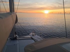 A serene view of a sailboat at sunset, showcasing the tranquil waters and vibrant sky — perfect for peaceful evening cruises.
