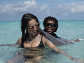 A joyful interaction as two individuals swim with a stingray in crystal-clear waters, showcasing a unique wildlife experience in a tropical paradise.