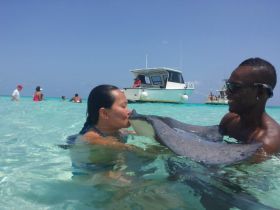 A thrilling encounter as a woman kisses a stingray while being guided by a local expert in the clear waters — a unique wildlife experience in the Bahamas.