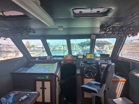 The interior of a boat's helm showcases a well-equipped cabin with navigation tools and fishing gear, perfect for a day out on the water.