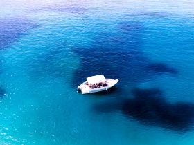 Aerial view of a speedboat cruising through crystal-clear turquoise waters, showcasing the beauty of a perfect day on the water.