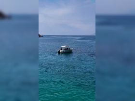 A boat navigates through crystal-clear waters, showcasing a serene day on the water — perfect for exploring coastal destinations.
