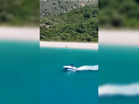 A speedboat glides through the crystal-clear waters near a secluded beach, showcasing the perfect blend of adventure and natural beauty.