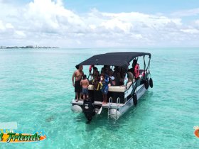 A lively group enjoys a day on a pontoon boat in crystal-clear waters, perfect for swimming and fun under the sun.