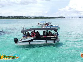 A lively group enjoys a day on the water aboard a pontoon boat, surrounded by friends and clear turquoise waters — perfect for a fun sandbar stop.