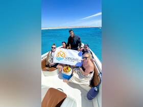 A lively group poses on a boat holding a banner for Sunghada Boat Tour, showcasing a fun day out on the water under the bright sun.