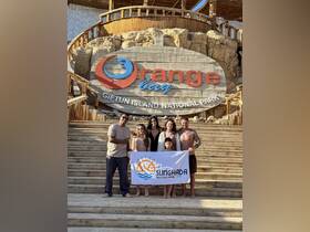 A joyful family poses with a banner for Sunghada Boat Tour at Orange Bay, Giftun Island National Park, capturing the essence of their memorable day on the water.