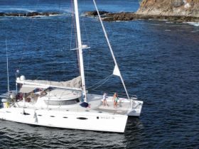 Two children enjoy the deck of a catamaran named 'WHY NOT I', showcasing a fun day on the water.