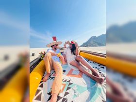 A couple enjoys a sunny day on a boat at the beach, showcasing a perfect blend of relaxation and romance in a picturesque setting.