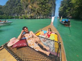 Two friends relax on the deck of a traditional boat, enjoying the stunning turquoise waters and beautiful scenery — a perfect day for sunbathing and exploration.