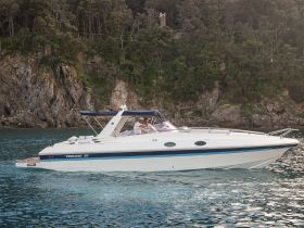 A sleek speedboat glides through clear waters, showcasing its elegant design against a stunning rocky backdrop — perfect for adventurous outings on the water.