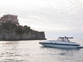A scenic view of a boat cruising near a picturesque coastline, showcasing the beauty of the landscape and the joy of boating adventures.