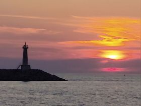 A stunning sunset view behind a lighthouse, creating a picturesque scene perfect for evening boat trips and coastal explorations.