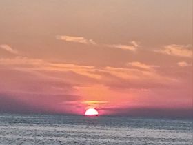 A stunning sunset over the ocean, showcasing vibrant hues of pink and orange — perfect for romantic evenings or serene moments on the water.