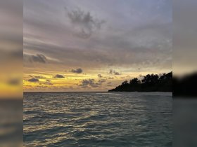A stunning sunset over tranquil waters, showcasing a beautiful coastline — perfect for capturing the serene beauty of nature.