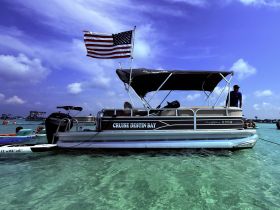 A lively scene featuring a pontoon boat anchored in clear waters, with guests enjoying the sun and swimming nearby — perfect for a fun day on the water.