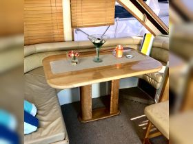 A cozy dining area inside a boat featuring a stylish table set with a martini glass and decorative flowers, perfect for intimate gatherings on the water.