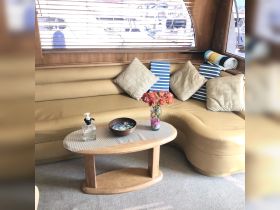 Cozy interior seating area of a boat featuring plush cushions, a decorative table, and a vase of flowers, perfect for relaxing while on the water.