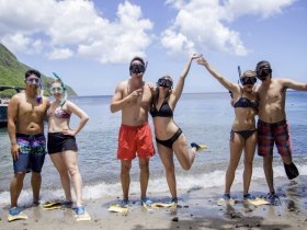 A lively group of friends poses excitedly on the beach, ready for a snorkeling adventure — perfect for capturing fun moments during a tropical getaway.