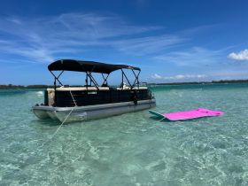 A pontoon boat anchored in crystal-clear waters, showcasing a perfect spot for relaxation and water activities.