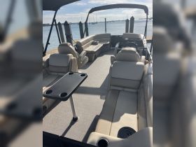 Interior view of a spacious boat lounge area featuring comfortable seating and a helm, perfect for relaxing on the water.