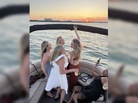 A lively group of friends celebrates at sunset on a boat, enjoying cocktails and each other's company — perfect for unforgettable party moments on the water.