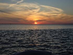 A stunning sunset over calm waters, with the silhouette of a boat in the foreground — perfect for capturing the beauty of evening cruises.