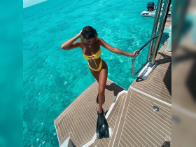 A woman in a vibrant yellow bikini prepares to dive into the crystal-clear waters, showcasing the excitement of snorkeling adventures in a tropical paradise.