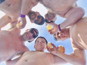 A cheerful group of friends, including a child, enjoys drinks together under the sun, capturing a fun moment during their boating adventure.