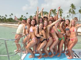 A vibrant group of friends celebrates on a boat, enjoying the sun and sea — perfect for beach parties and unforgettable summer memories.