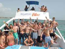 A lively group of young adults celebrates aboard a boat, enjoying drinks and good vibes on the water — perfect for party cruises and group outings.