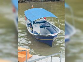 A small boat named 'AYIE 2' is docked on calm waters, showcasing its sleek design and comfortable seating, perfect for leisurely trips.