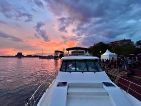 A stunning sunset view from the deck of a boat, with a vibrant sky and lively harbor scene in the background, perfect for evening cruises and social gatherings.