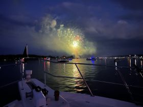 A stunning view of fireworks lighting up the night sky over the water, captured from the deck of a boat — perfect for celebrating special occasions.