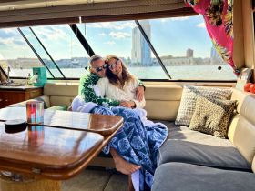 A cozy moment inside a boat's cabin, featuring a couple enjoying each other's company with a scenic view outside — perfect for romantic getaways on the water.