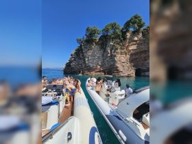 A lively group enjoys a day out on the water, surrounded by stunning cliffs and clear blue skies — perfect for a memorable boating adventure.