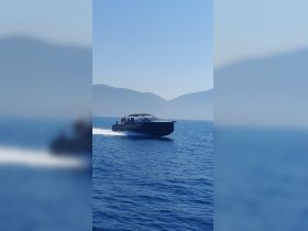 A sleek boat speeds through clear blue waters, with passengers enjoying the ride against a stunning mountainous backdrop — perfect for adventure seekers on the water.
