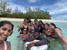 A joyful group of friends enjoys a fun day swimming in crystal-clear waters, capturing memories against a beautiful beach backdrop.