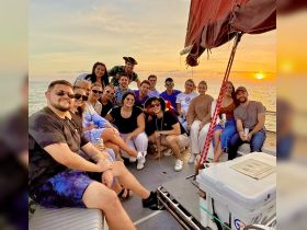 A lively group enjoys a sunset celebration aboard a boat, capturing the joy of friendship and adventure on the water.
