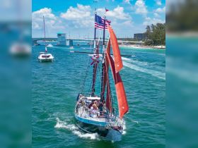 A vibrant sailing experience with a group aboard a classic vessel, navigating through picturesque waters under a sunny sky.
