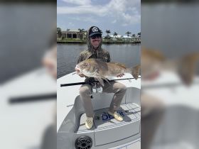 An angler proudly displays his catch on a fishing boat, showcasing the thrill of a successful day on the water.