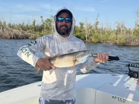 A proud angler displays his catch aboard a boat, showcasing the thrill of fishing in scenic waters.