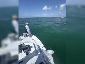 A fisherman casts his line from the bow of a boat, enjoying a day on the open ocean — perfect for fishing enthusiasts seeking adventure.