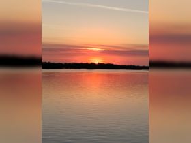 A stunning sunset casts vibrant colors over the water, creating a picturesque reflection — perfect for serene evening boat trips.