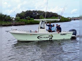 A cheerful group waves from aboard the 'Drop 'Em Down' fishing charter boat, ready for an exciting day on the water.