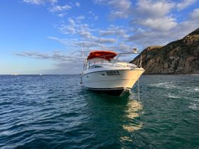 A stunning view of a yacht anchored in calm waters, showcasing its sleek design against a backdrop of scenic hills and a beautiful sky.