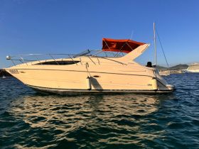 A sleek yacht glides through clear waters, showcasing its elegant design against a vibrant blue sky — perfect for luxury outings and coastal adventures.