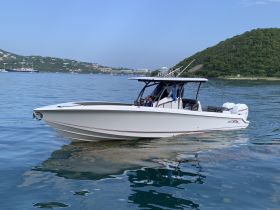 A family enjoys a day on the water aboard a sleek boat, cruising through calm waters with scenic hills in the background.