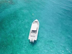 Aerial view of a sleek speedboat cruising through crystal-clear turquoise waters, perfect for exploring coastal destinations.