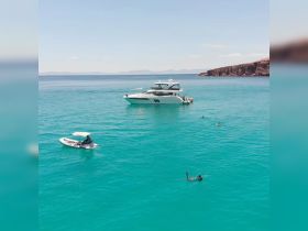 A vibrant scene of guests snorkeling and enjoying the turquoise waters near a luxurious yacht, perfect for a day of adventure and relaxation on the water.